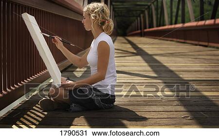 Stock Image - Young artist painting on a bridge. Fotosearch