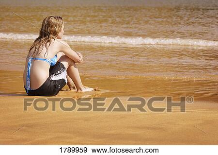 Young girl sitting on beach View Large Photo Image Stock Photo - Young girl sitting on beach. Fotosearch