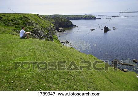 Stock Photo - Young man observing the breathtaking view of Northern Ireland. Fotosearch