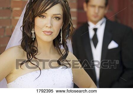 Stock Photography - Bride in wedding dress with groom in background. Fotosearch