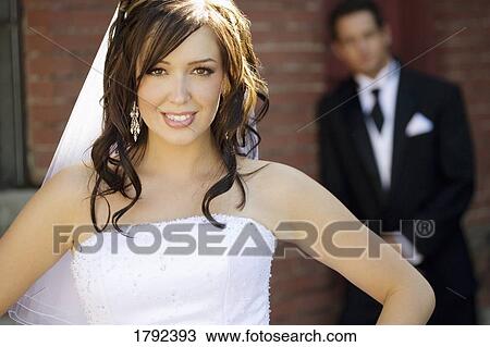 Stock Image - Bride posing in front of groom. Fotosearch