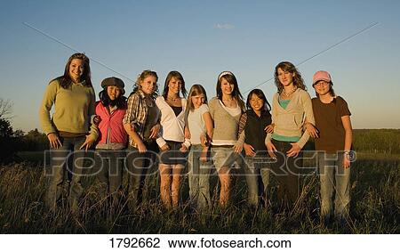 Stock Image - Group of women and girls arm-in-arm in field. Fotosearch
