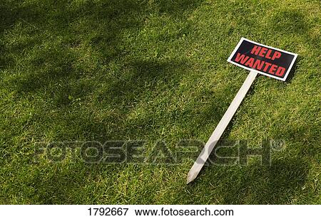Stock Photo - Help wanted sign laying on grass. Fotosearch