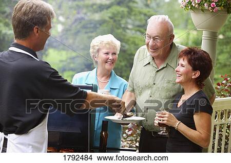 Man barbecuing and serving burgers View Large Photo Image Picture - Man barbecuing and serving burgers. Fotosearch