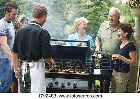 Man barbecuing burgers and talking with group of people View Large Photo Image Stock Image - Man barbecuing burgers and talking with group of people. Fotosearch