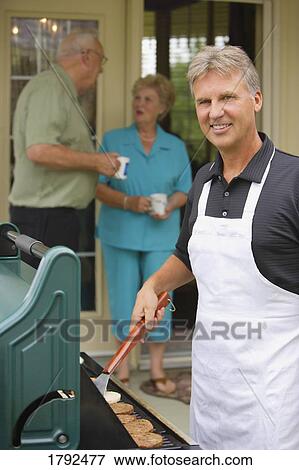 Man barbecuing burgers View Large Photo Image Stock Photo - Man barbecuing burgers. Fotosearch