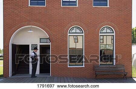 Stock Photo - Man in front of an old-fashioned post office. Fotosearch
