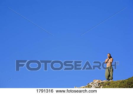 Stock Photograph - Man meditating on hilltop. Fotosearch