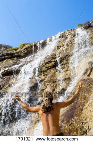 Man standing under waterfall with outstretched arms View Large Photo Image Stock Image - Man standing under waterfall with outstretched arms. Fotosearch