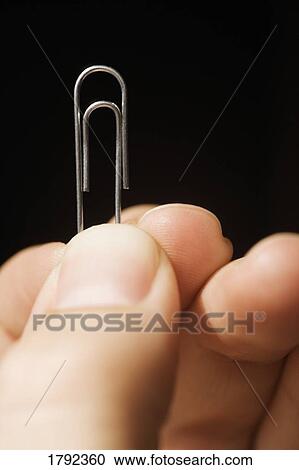 Person holding up a paperclip View Large Photo Image Stock Image - Person holding up a paperclip. Fotosearch