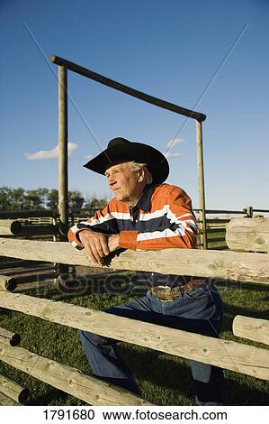Stock Image - Rancher leaning on a corral. Fotosearch