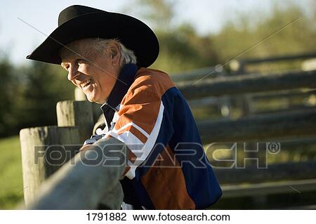 Stock Image - Rancher leaning on a corral. Fotosearch