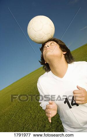 Stock Photo - Soccer player balancing a ball on his head. Fotosearch