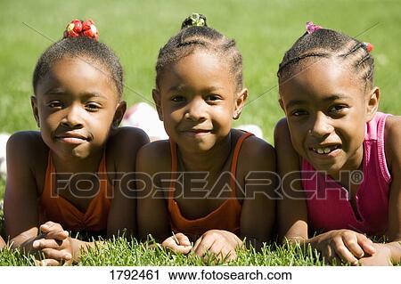 Three girls laying on grass View Large Photo Image Stock Image - Three girls laying on grass. Fotosearch