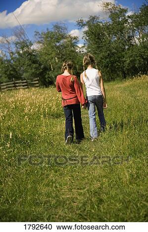 Stock Image - Two girls walking in a field. Fotosearch