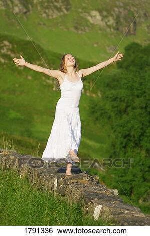 Stock Photograph - Woman balancing on rock wall ledge. Fotosearch