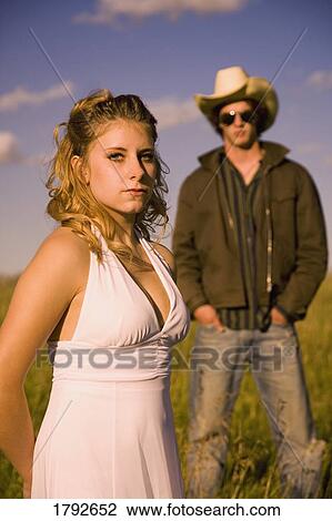 Woman in field with man in background View Large Photo Image Stock Image - Woman in field with man in background. Fotosearch