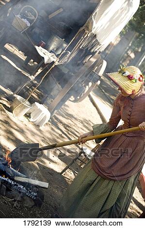 Woman in old-fashioned clothing with shovel tending to fire View Large Photo Image Stock Photo - Woman in old-fashioned clothing with shovel tending to fire. Fotosearch
