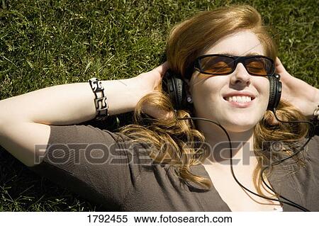 Woman laying on grass with headphones and sunglasses on View Large Photo Image Stock Photography - Woman laying on grass with headphones and sunglasses on. Fotosearch