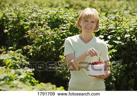 Stock Photo - Woman picking raspberries. Fotosearch