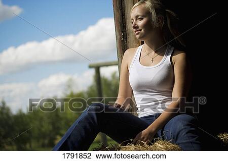 Stock Image - Woman sitting in a barn loft. Fotosearch