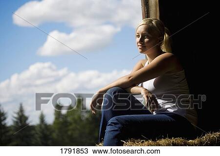 Stock Image - Woman sitting in a barn loft. Fotosearch