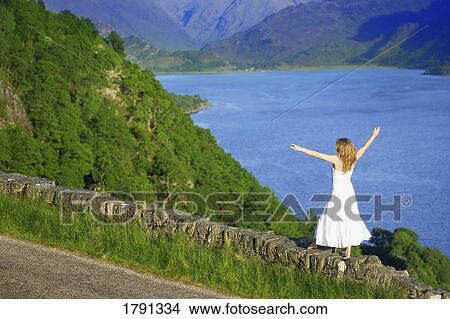 Picture - Woman walking along rock wall. Fotosearch