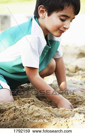 Stock Photo - Young boy playing in sand. Fotosearch