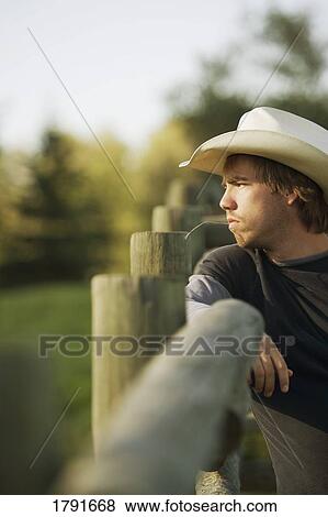 Young cowboy leaning on corral View Large Photo Image Stock Photo - Young cowboy leaning on corral. Fotosearch