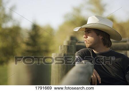 Young cowboy leaning on corral View Large Photo Image Stock Photo - Young cowboy leaning on corral. Fotosearch