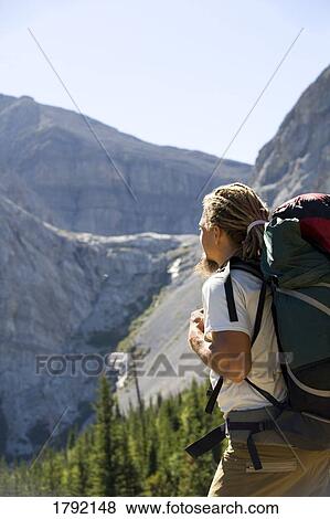 Stock Photo - Young man hiking in mountains. Fotosearch