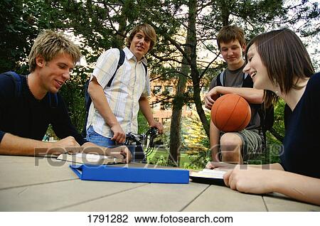 Young people gathered around a table View Large Photo Image Stock Image - Young people gathered around a table. Fotosearch