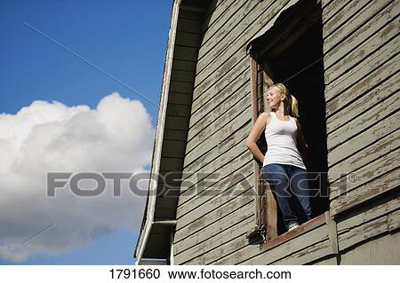 Stock Image - Young woman in barn loft. Fotosearch