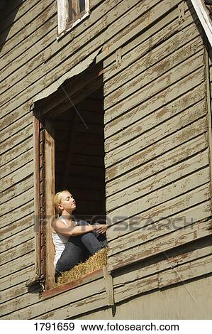 Stock Photo - Young woman sitting in barn loft. Fotosearch