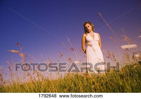 Stock Photo - Young woman standing in a field. Fotosearch