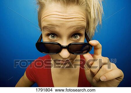 Young woman wearing sunglasses looking surprised View Large Photo Image Picture - Young woman wearing sunglasses looking surprised. Fotosearch