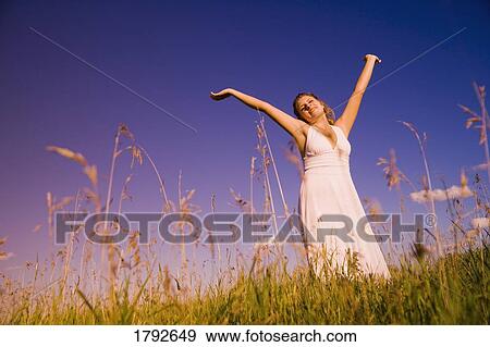 Young woman worshipping in a field View Large Photo Image Stock Photo - Young woman worshipping in a field. Fotosearch