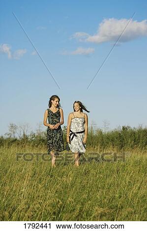 Young women walking in field View Large Photo Image Stock Image - Young women walking in field. Fotosearch