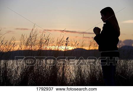 A teenage girl prays at sunset by the ocean. View Large Photo Image Stock Photo - A teenage girl prays at sunset by the ocean.. Fotosearch