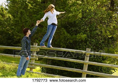 Stock Image - Balancing on fence rail. Fotosearch