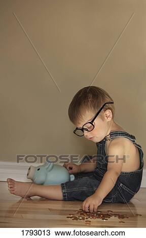 Boy putting money into a piggy bank View Large Photo Image Stock Image - Boy putting money into a piggy bank. Fotosearch