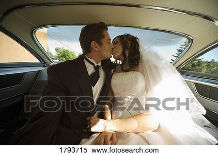 Stock Photography - Bride and groom kissing in the backseat of a car. Fotosearch