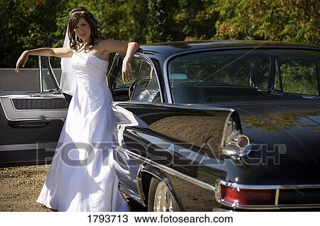 Bride standing outside wedding car View Large Photo Image Stock Image - Bride standing outside wedding car. Fotosearch