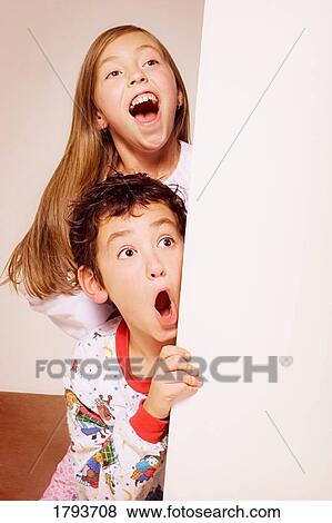 Stock Photo - Brother and sister peeking around corner. Fotosearch