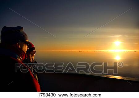 Stock Image - Couple watching sunset. Fotosearch