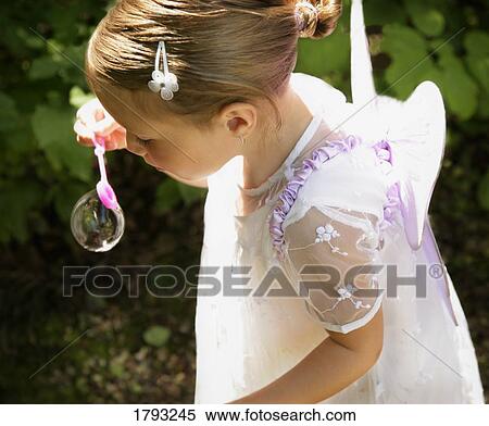 Stock Photography - Girl dressed as a fairy blowing bubbles. Fotosearch