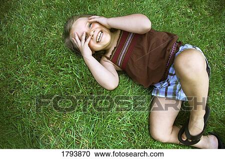Stock Image - Little girl laying on grass. Fotosearch