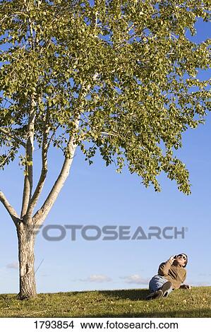 Picture - Man resting under tree. Fotosearch