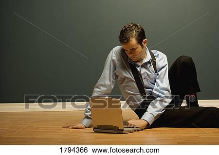 Stock Photograph - Man using laptop on the floor. Fotosearch