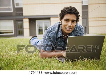 Man working on a laptop in grass View Large Photo Image Stock Image - Man working on a laptop in grass. Fotosearch